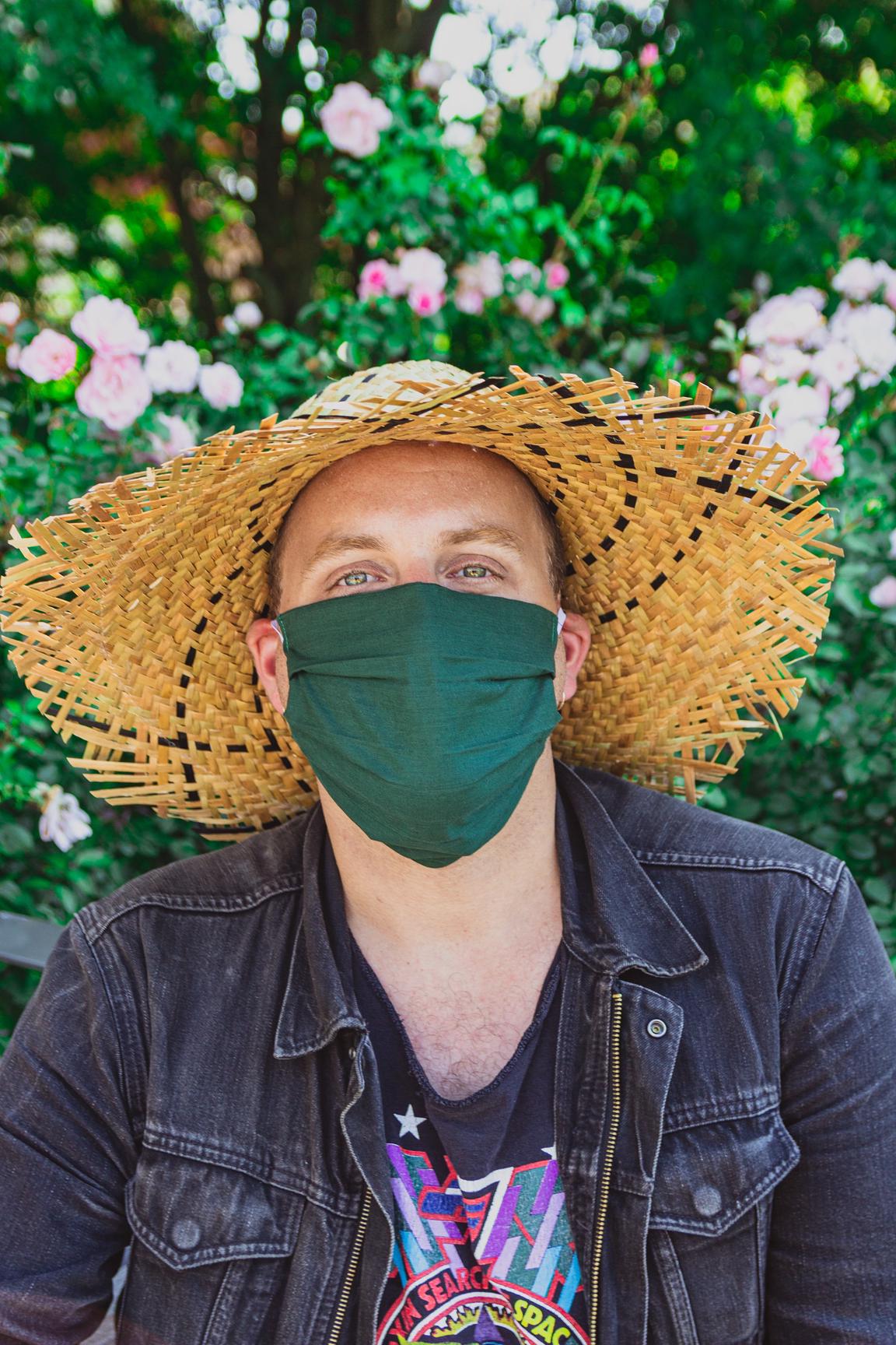 A picture of Stewart Legere wearing a big, straw, sun hat and a green covid-19 mask.