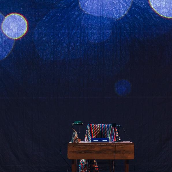 The set of Final Recordings... an antique chair and table on top of a circular cottage rug. 