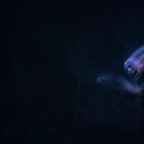 A black background. A ghostly, blurred image of a man in blue/purple light, seemingly screaming in agony. 